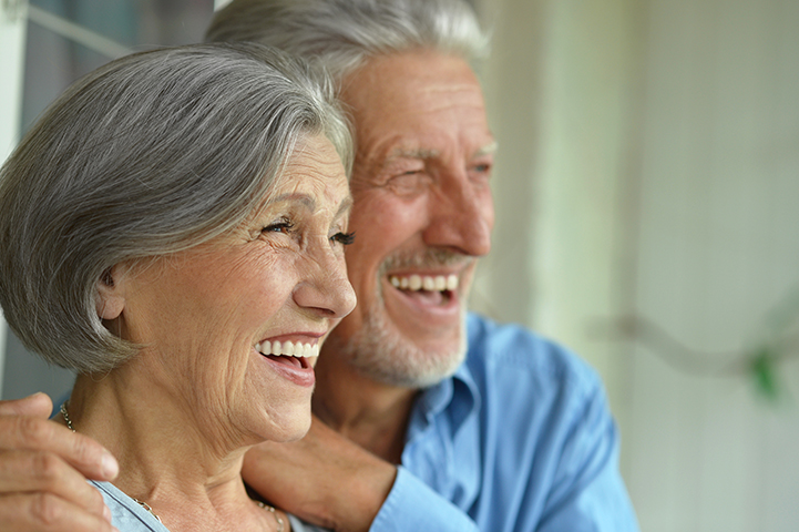 An image of an older couple smiling with full mouth dental implants.